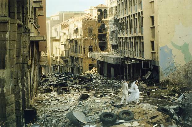 Just married, 23 years old Abed (Muslim groom) and 19 years old Arige (Christian bride) walk through the bombed ruins of Beirut, Lebanon, 1983.