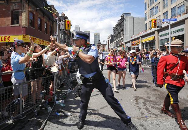 Police officer Keiss Zamir high-fives the crowd at the Toronto Pride Parade in Toronto on June 30, 2013.