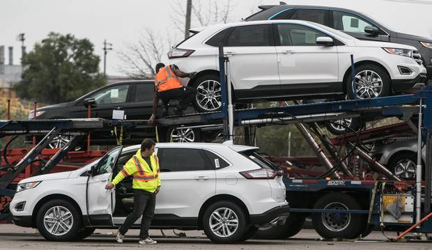 Workers at the Oakville Ford plant load cars onto a truck for shipment.