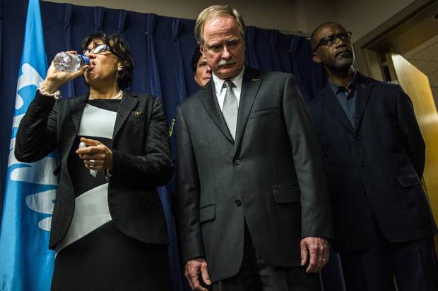 Flint Mayor Karen Weaver drinks from a bottle of water beside Keith Creagh, director of Michigan’s Department of Environmental Quality, as Governor Rick Snyder fields questions from reporters on Jan. 27.