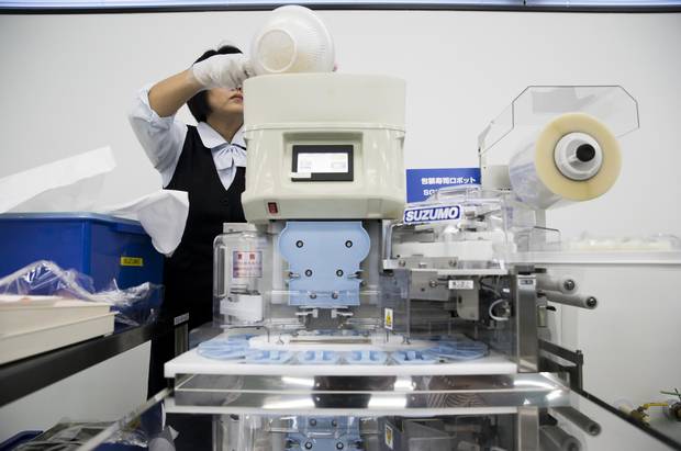 An employee puts a bowl of rice into a Suzumo Machinery Co. sushi machine.