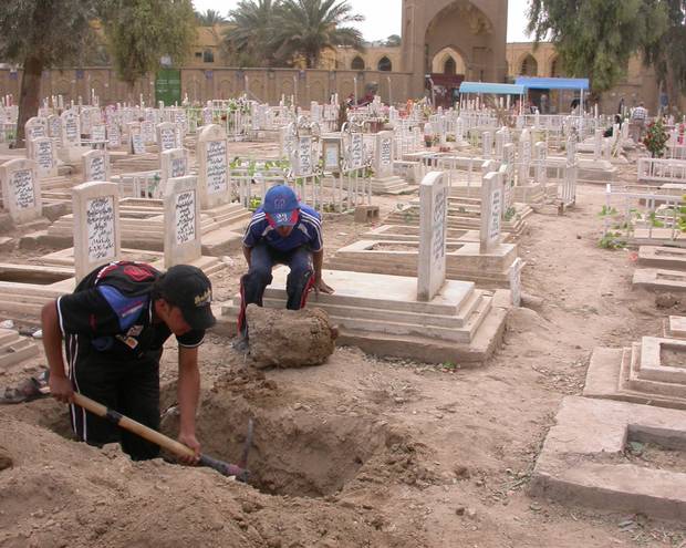 Residents of a Baghdad neighbourhood dig a fresh plot in the graveyard in 2008.