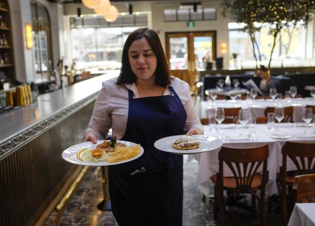 A waitress carries beef tartare and apple tart at the Royale Brasserie.