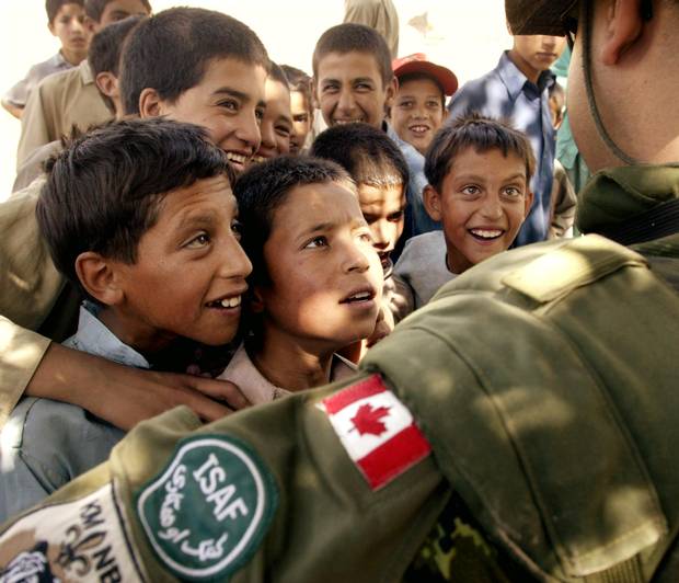 A Canadian corporal is surrounded by curious Afghan children as he and Canadian military engineers tour local villages around their base camp in Kabul Afghanistan, on Aug. 18, 2003.