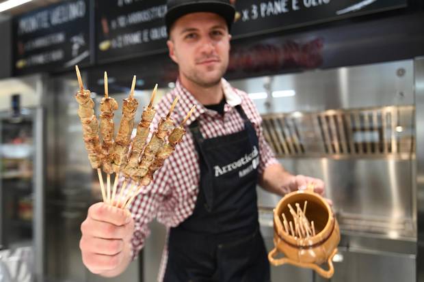 A vendor presents special Italian sheep 'kebab' at a stand during a press tour at FICO Eataly World agri-food park in Bologna on November 9, 2017. FICO Eataly World, said to be the world's biggest agri-food park, will open to the public on November 15, 2017. The free entry park, widely described as the Disney World of Italian food, is ten hectares big and will enshrine all the Italian food biodiversity.