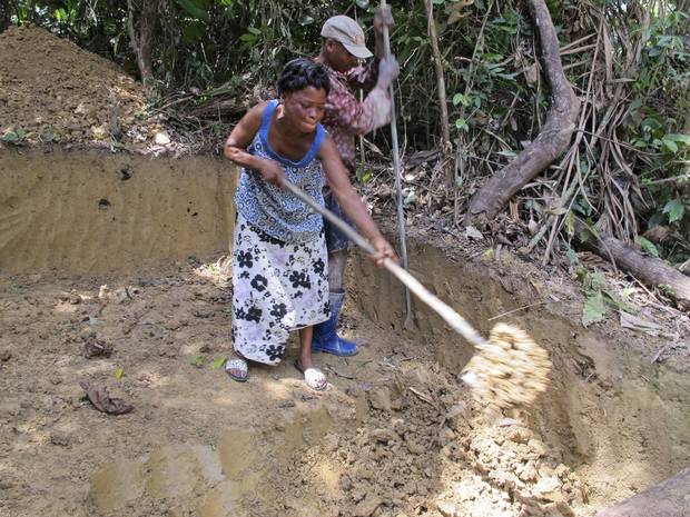 Mami Basikawike, left, and Germain Kambale dig up soil as they search for gold at a small mining site near Metale. She says female miners are subjected to a double standard by being required to dress modestly and avoid wearing ripped clothes.