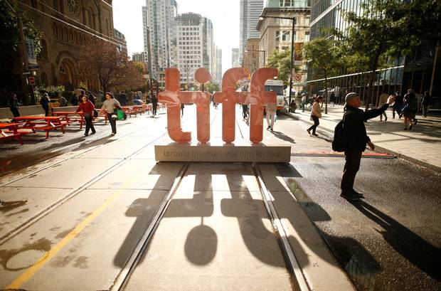 A man takes selfie in front of a TIFF sign on a closed city street in Toronto on Sept. 7, 2017.