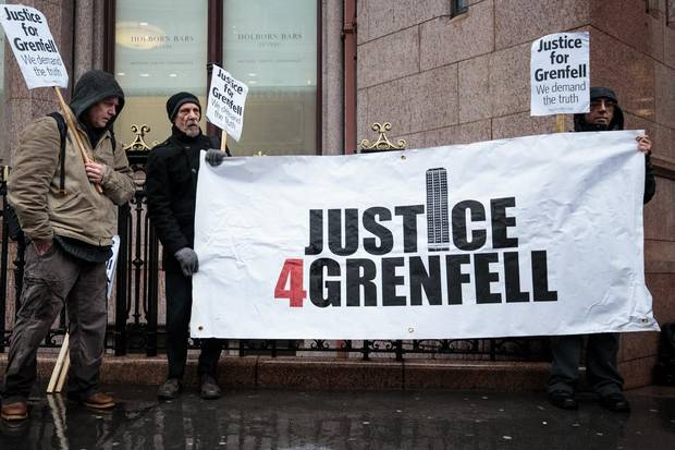 Protesters stand with a banner and placards outside Holborn Bars before a two-day hearing as part of the inquiry into the Grenfell Tower fire on Dec. 11, 2017 in London, England.