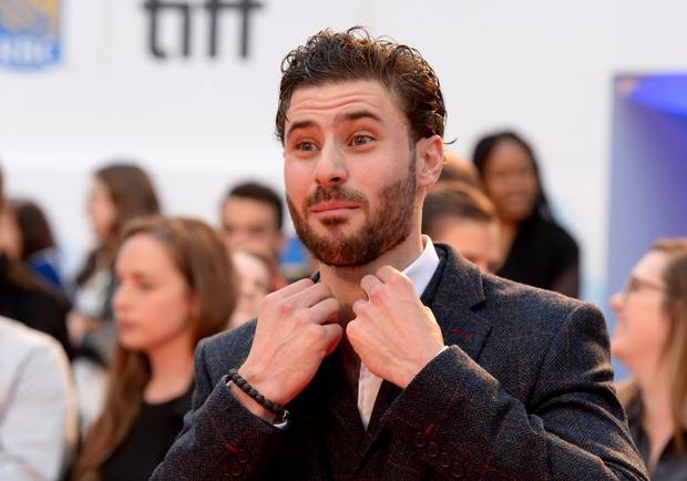 Actor Tom Datnow adjusts his collar as he arrives on the red carpet.