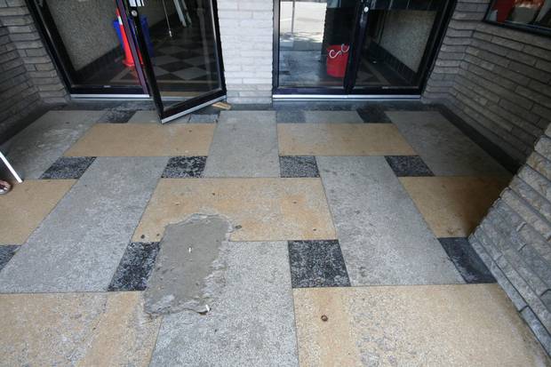 The checkerboard terrazzo flooring has been worn away or damaged.