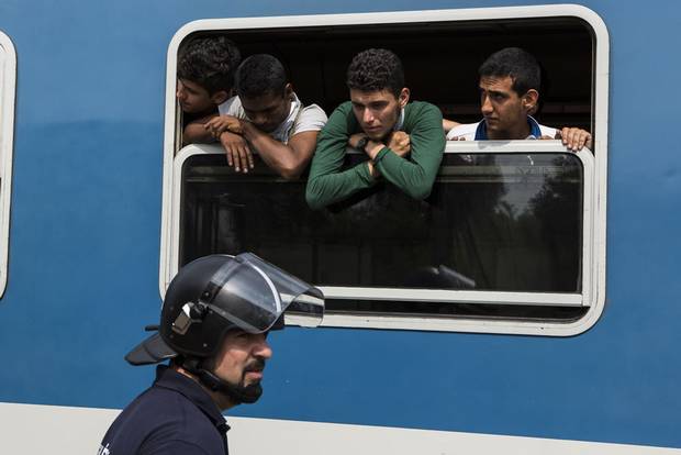 Syrian refugee Khaled Allak leans out of a train window on Sept. 3, 2015 while en route from Budapest, Hungary to a refugee camp in Bicske. After learning the train was not going to Germany as hoped, Mr. Allak and other young Syrians escaped from the train and trekked over land to Germany.