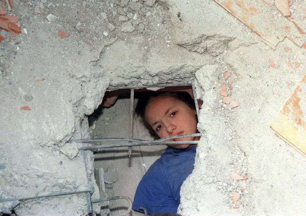 A 13-year-old girl identified only as Ozge looks through a hole in the rubble of a collapsed building while waiting to be rescued in Sakarya, Turkey, on Aug. 18, 1999.