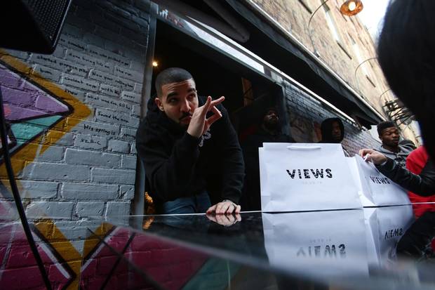 Drake poses for photos as he hands out T-shirts at a pop up shop in Toronto to promote his new album on Sunday. 