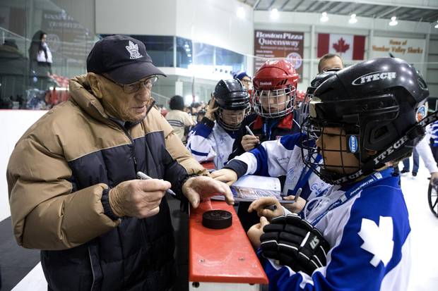 Johnny Bower signs a puck for nine year old Marco Rutunis during the Leaf's Skate for Easter Seals Kids event in Toronto in 2014.