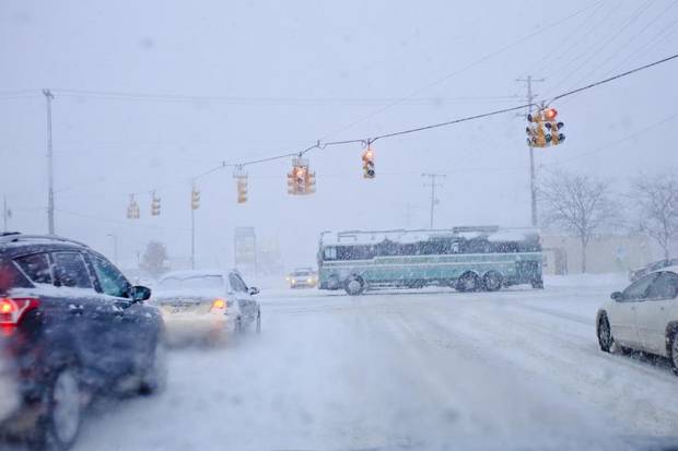 A bus passes through the intersection of Lake Michigan Dr. and Wilson Ave. in Walker, Mich., Tuesday, Nov. 18, 2014. Lake-effect storms in Michigan produced gale-force winds and as much as 18 inches of snow, and cancelled several flights at the Grand Rapids airport.