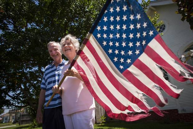 Caroline and Don McClure stand outside their home in New Orleans on July 16, 2015, holding their tattered American flag which survived Hurricane Katrina.