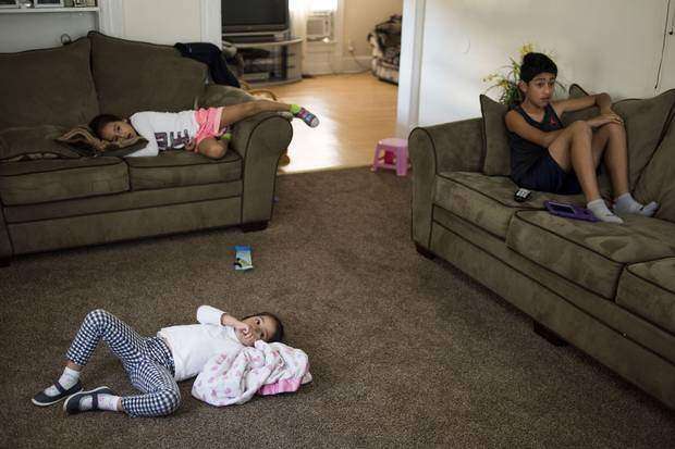 Mackaylah, Evelyn and Anthony watch TV in their living room.