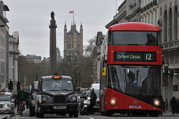 A red London bus waits at traffic lights in central London on March 20, 2017. London is trying out a system of bus-mounted cameras to monitor car use and issue tickets.