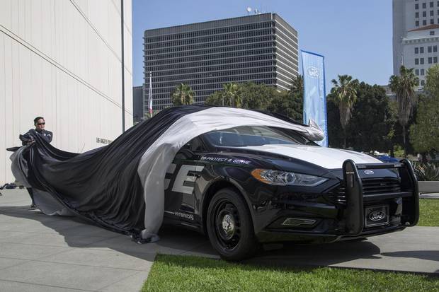 An LAPD officer unveils one of two new Ford Fusion hybrid police cars at Los Angeles Police Department headquarters on April 10, 2017.
