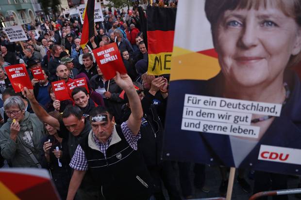 In Finsterwalde, Germany, protesters and hecklers chant ‘Merkel must go!’ and ‘Traitor to the people!’ while holding up red slips of paper that read: ‘Red card for Merkel!’