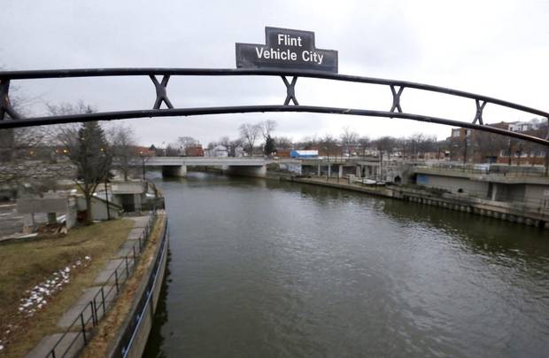 This Jan. 26, 2016 file photo shows a sign over the Flint River noting Flint, Mich., as Vehicle City. In proposing a tougher limit for lead in drinking water, Gov. Rick Snyder wants to lift Michigan from the depths of the Flint crisis to being a model for water safety that can help assess whether the current national rules governing lead are too lax.