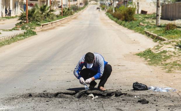 A Syrian man collects samples from the site of a suspected toxic gas attack in Khan Sheikhun, April 5, 2017.