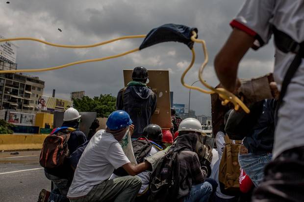 Protesters use an improvised slingshot to attack Venezuelan security forces during a protest against Venezuelan president Nicolas Maduro.