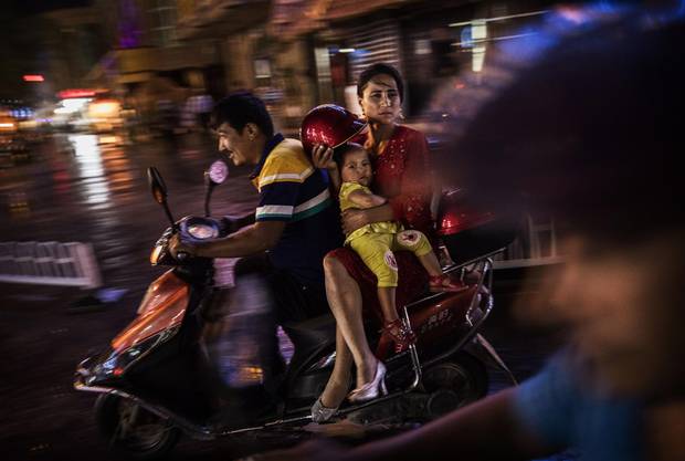 An ethnic Uyghur family ride a scooter on June 28, 2017 in the old town of Kashgar, in the far western Xinjiang province, China. 