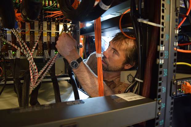 Matt Dobbs, an astrophysicist at McGill University and member of the CHIME team, works on the guts of the electronics used to process data from the experiment.