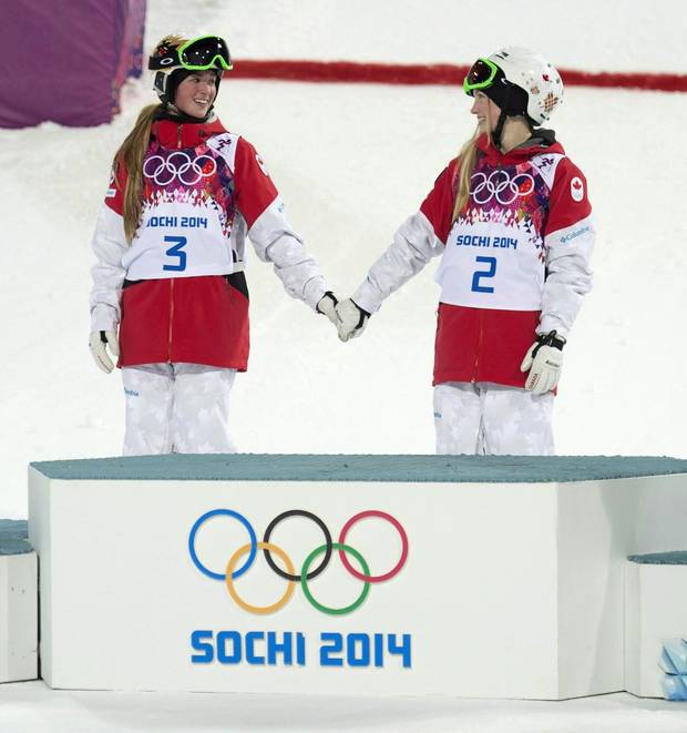 Canada's Justine Dufour-Lapointe and Chloe Dufour-Lapointe holds hands before climbing on the podium after winning the gold and silver medals in the moguls at the Sochi Winter Olympics Saturday February 8, 2014 in Sochi, Russia.