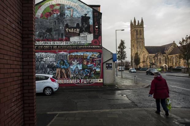 A local woman walks by a loyalist mural in Newtownards Road, a predominately protestant and loyalist neighbourhood in East Belfast, Northern Ireland.
