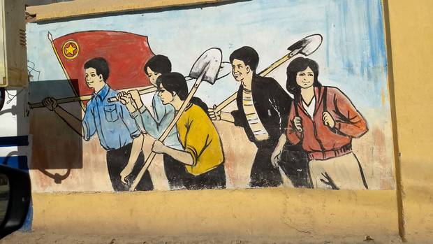 A wall painting in Xinjiang shows Uyghurs working happily under the Chinese flag.