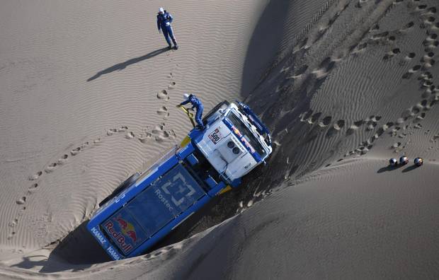 TOPSHOT - Kamaz Russian driver Eduard Nikolaev, co-drivers Evgeny Yakovlev and mechanic Vladimir Rybakov are stuck in the sand after their truck tipped over during the 2018 Dakar Rally Stage 5 between San Juan De Marcona and Arequipa in Peru, on January 10, 2018. Sebastien Loeb was forced to pull out of the Dakar Rally after a back injury suffered by his co-driver in a disastrous fifth stage won by defending champion Stephane Peterhansel.