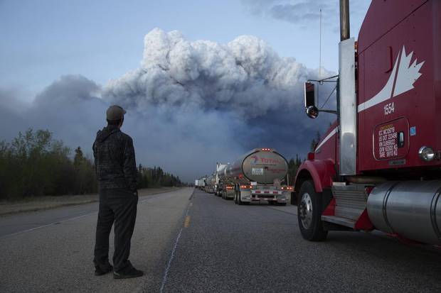 Drivers of a resupply convoy stand outside their vehicles south of Fort McMurray as a wildfire blocked the only highway to the city. Nearly 25,000 of Fort McMurray's 90,000 or so residents fled north to isolated oil industry work camps when the city was ordered evacuated, but supplies there quickly ran low.