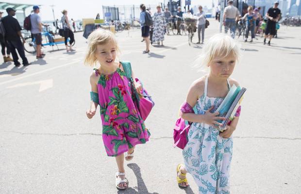 Six-year-old twin sisters Billie Page, right, and Izzy Page, left, walk off the ferry as they temporarily attend Nelson Mandela Park Public School.
