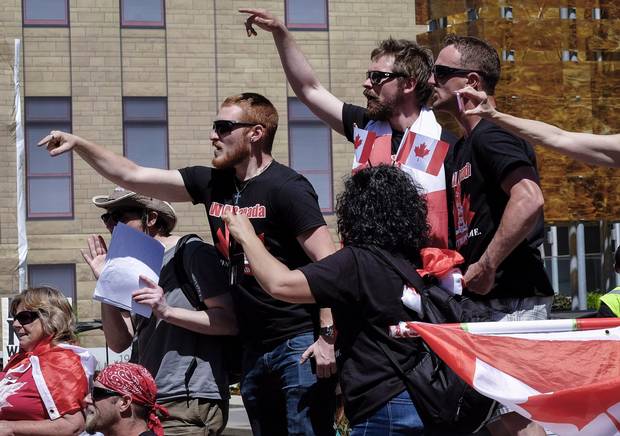 Anti-Islamists shout at counter protesters from behind a police line during an anti-Islam rally in Calgary, Alta., Sunday, June 25, 2017.