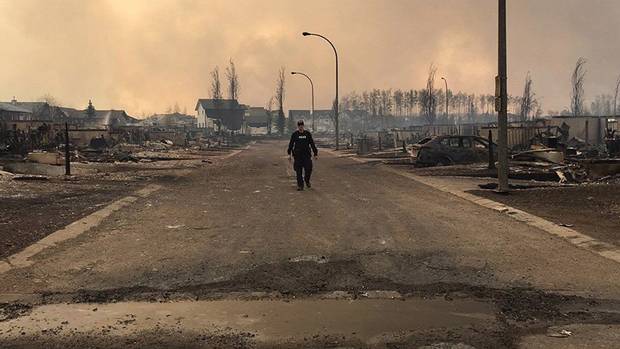 An RCMP officer surveys the damage on a street in Fort McMurray.