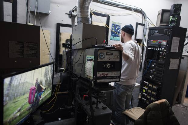 Malcolm Dow works in the projection room with modern and vintage equipment.