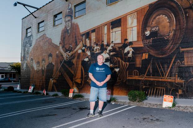Ron Faraday, president of the Greater Pittston Historical Society and a production supervisor at Greiner Packaging, stands in front of a mural commemorating the Pennsylvania town’s history.