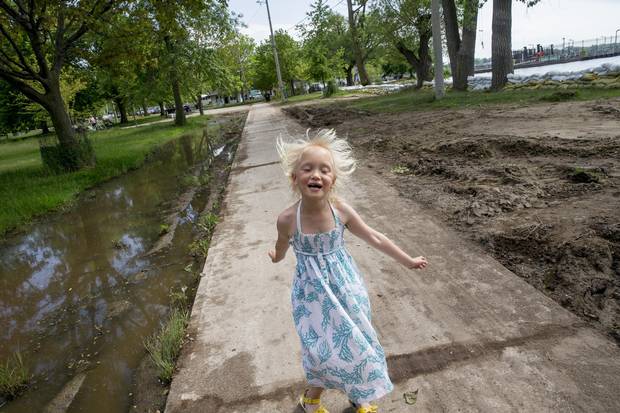 Billie Page walks near large puddles of water and a shoreline lined with sand bags on Ward's Island.