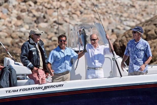 July 2, 2007: Then-president George W. Bush, right, and former president George H.W. Bush, look on as Russian President Vladimir Putin displays his catch during a fishing outing in Kennebunkport, Me., on Monday, July 2, 2007. Second from left is fishing guide Billy Bush.