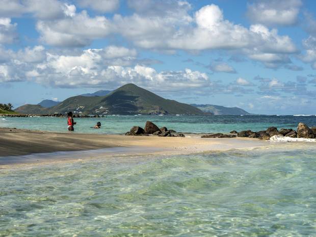 People swim in the Caribbean Sea in Long Haul Bay, Nevis. Newcastle Bay and the island of St. Kitts are in the background.