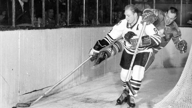 Peerless crowd-pleaser Eddie Shack (23) of the Toronto Maple Leafs literally drapes himself around Chicago Black Hawks' great Bobby Hull in battle for puck during Saturday action, December 25,1965, at Maple Leaf Gardens in Toronto.