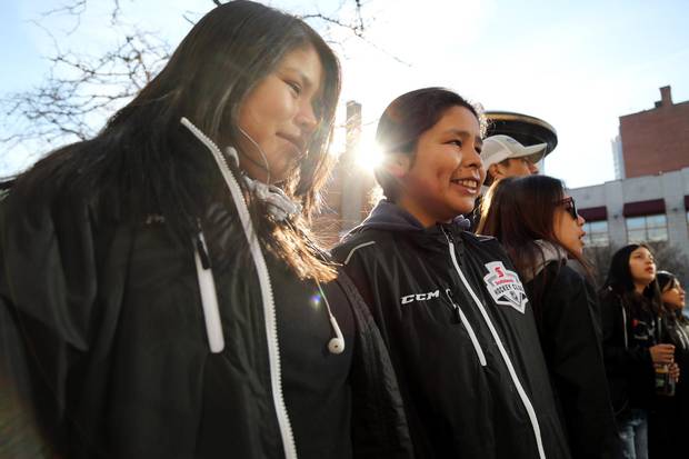 Ryanne Wapoose (left) and Danielle Jacob (centre), members of the Rez Girls 64 Wolves hockey team, at the ByWard Market in Ottawa.