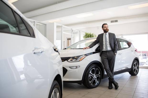 Hugo Jeanson, co-owner of Bourgeois Chevrolet, poses for a photograph with a Chevrolet Bolt electric car at the car dealership in Rawdon, Quebec, 70 kilometres north of Montreal, on Thursday, February 8, 2018. This dealership in a small town in Quebec sells the most electric and hybrid vehicles in Canada.