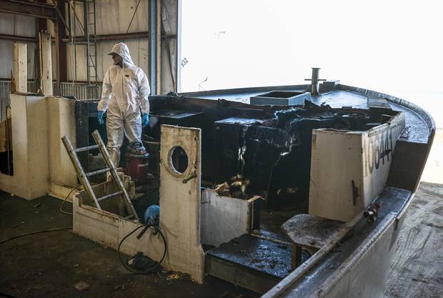 An employee at the A.F. Theriault & Son Ltd. boatyard begins stripping the fire-damaged sections of the lobster boat 