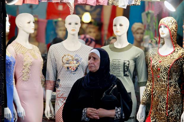 An Iraqi woman stand in front of a shop for women's clothes in the souk in the East of Mosul, Iraq, July 22,2017.