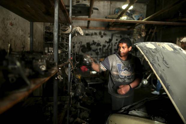 Mahmoud Yazji repairs a car at a garage.