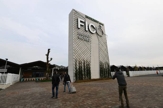 People walk at the entrance to FICO Eataly World agri-food park in Bologna on November 9, 2017. FICO Eataly World, said to be the world's biggest agri-food park, will open to the public on November 15, 2017. The free entry park, widely described as the Disney World of Italian food, is ten hectares big and will enshrine all the Italian food biodiversity. / AFP PHOTO / Vincenzo PINTO