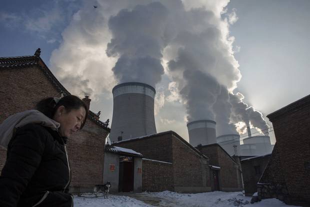 A woman walks out of her house next to a coal-fired power plant on Nov. 26, 2015, in Shanxi, China.